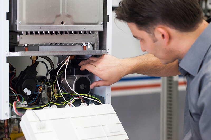 4 Important Heat Pump Maintenance Tips. Man checking out heat pump.